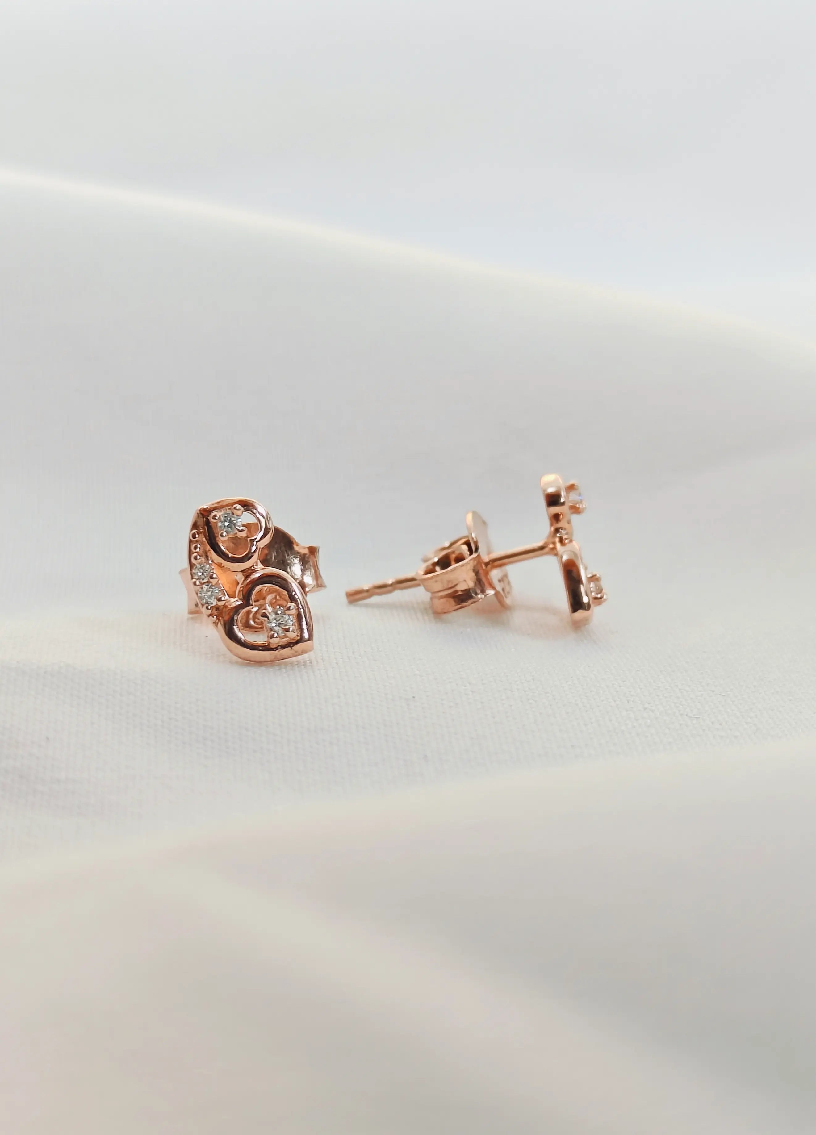 Rose gold heart-shaped earrings on a light background